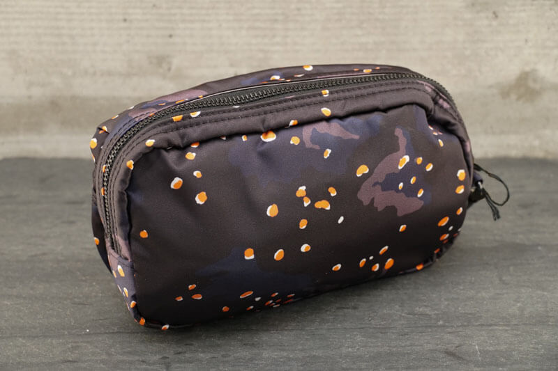 Porter PS Chip Camo Pouch About PS Chip Camo Series The ‘PS Chip Camo’ series is an original PORTER textile design inspired by camo print created for the desert environment in the 1980’s , characterized by the addition of pebbles . The camo print is also unique for its subtle colorway—navy, grey and black— with a pop of orange and white pebbles.